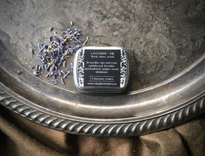 Back label of Ritual Aromatics Lavender + Fir Hand Rolled Incense Cones in a tin on a silver tray with loose lavender