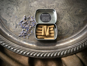 An open tin of Ritual Aromatics Lavender + Fir handmade Incense Cones on a silver tray with loose lavender