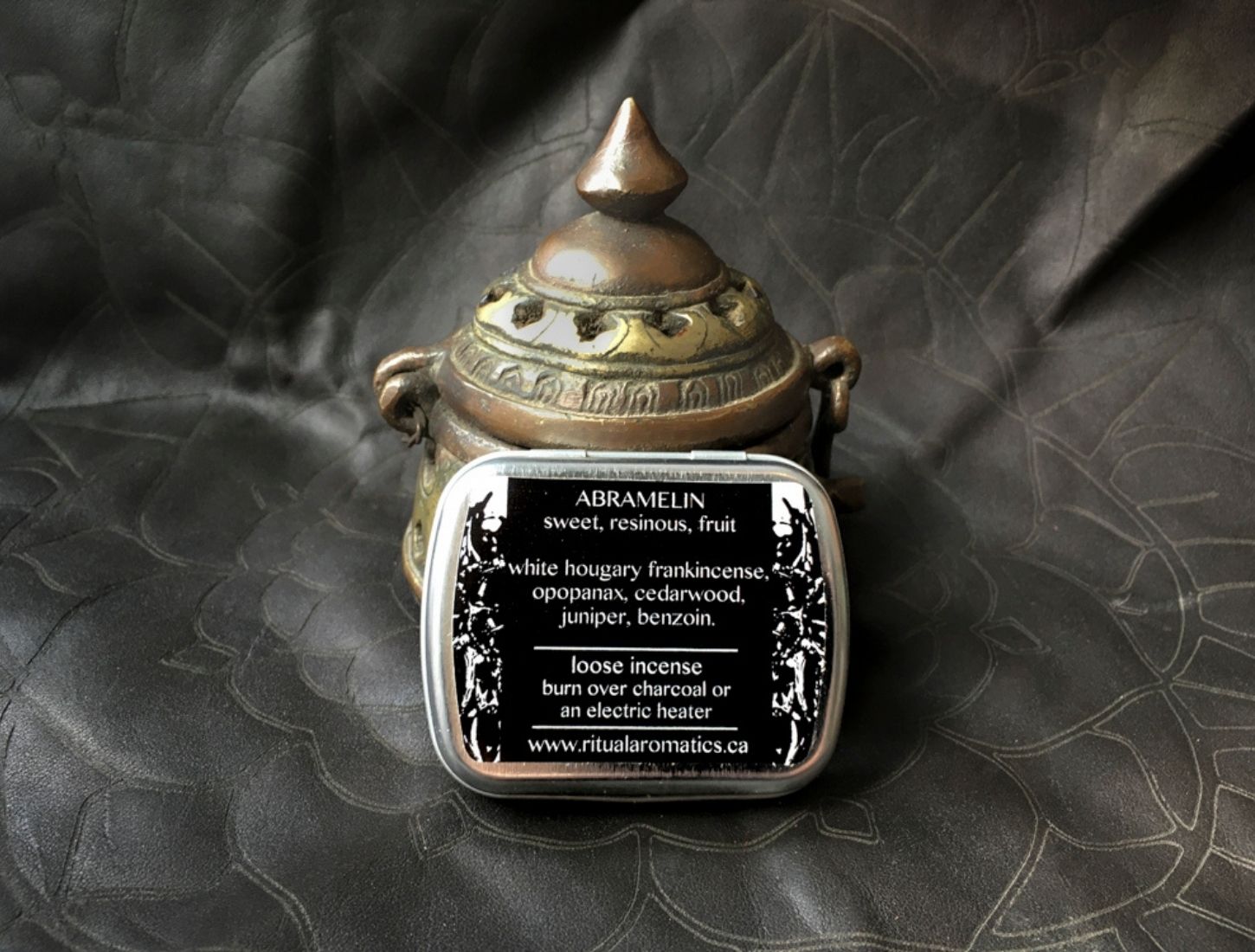 Back label of Ritual Aromatics Abramelin Loose Incense on gray leather in front of an antique brass incense burner