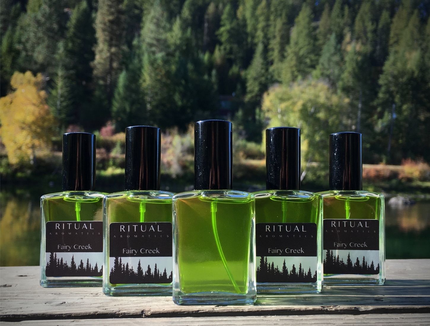 Ritual Aromatics Fairy Creek Natural Botanical Perfume bottles on a dock by water and trees